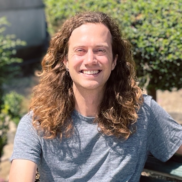 Stanford Rosenthal, smiling, seated on a bench outdoors