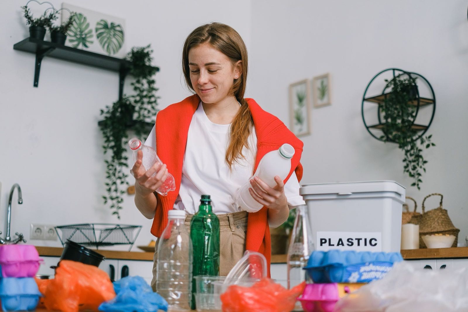 Person sorting through waste, with a bin labeled "plastic" nearby